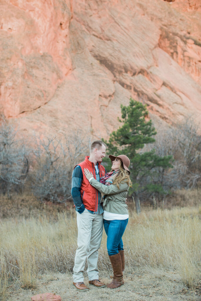 couple standing in embrace near red rocks 