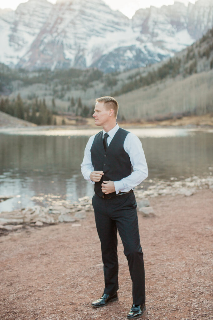 man wearing black suit with vest looking toward the mountains 