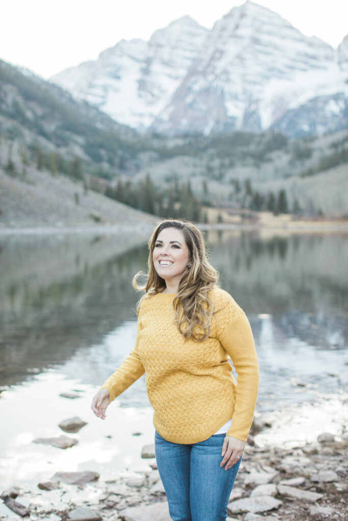 woman wearing yellow sweater with mountains in the distance 