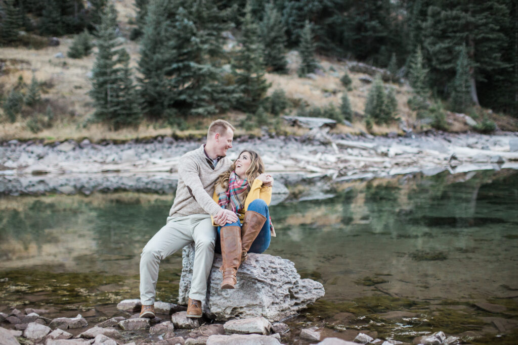 couple snuggling and laughing on a rock and enjoying nature 