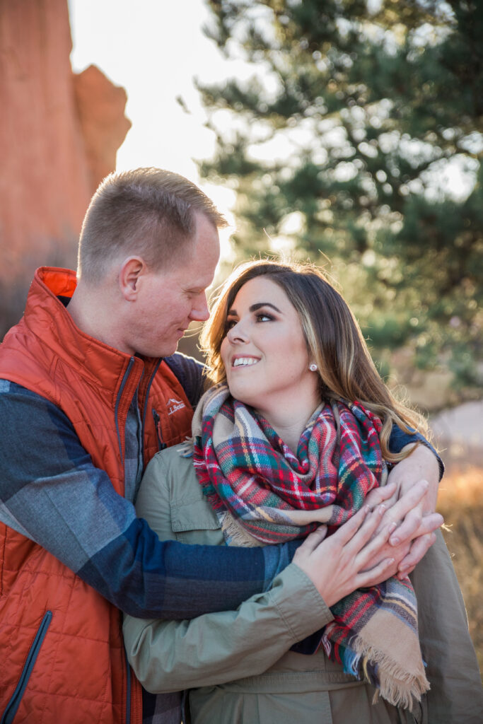 couple standing in embrace near red rocks 