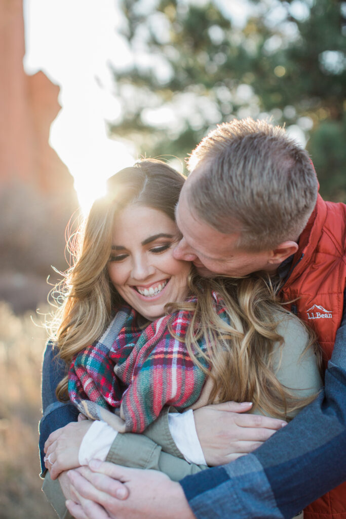 couple snuggling in embrace near red rocks 