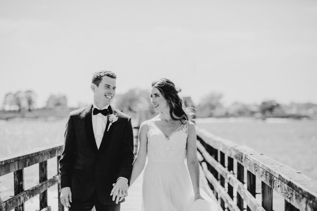 bride and groom holding hands and laughing on the dock