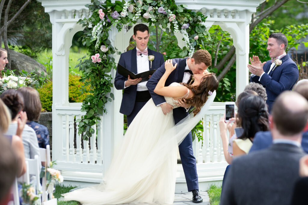 bride and groom at the alter groom dipping bride during first kiss