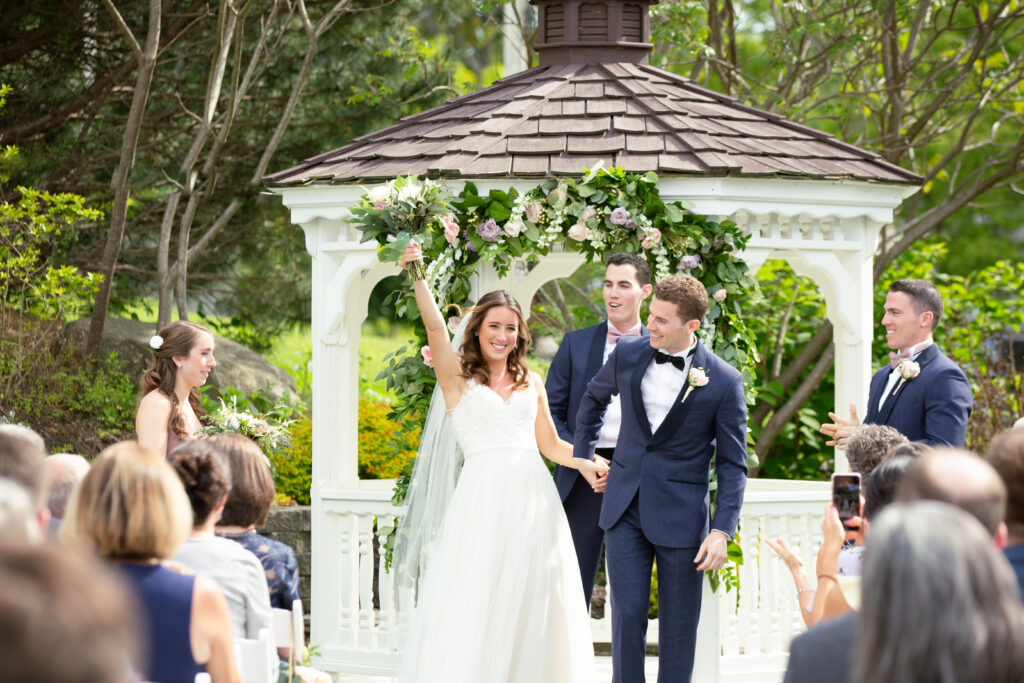 bride and groom celebrating as they walk down the aisle 