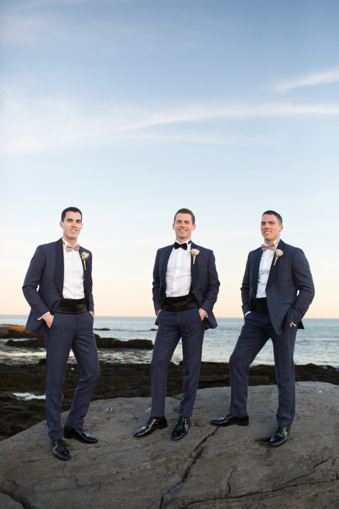 groomsmen on the rocks at the water