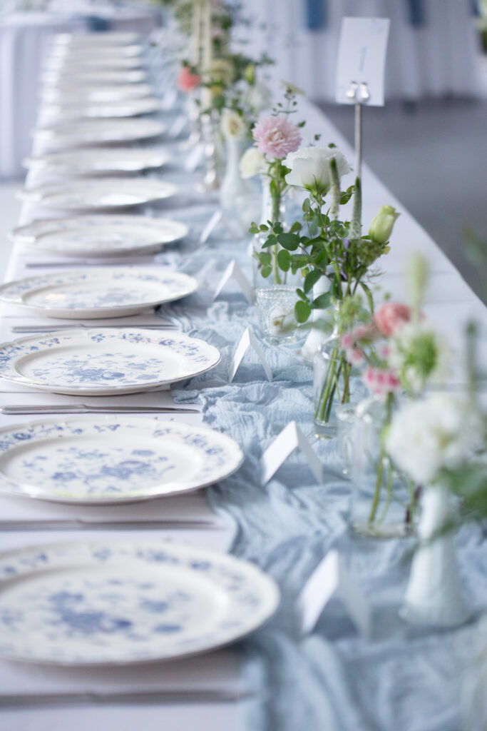 reception tables with blue and white patterned plates and linen table runner