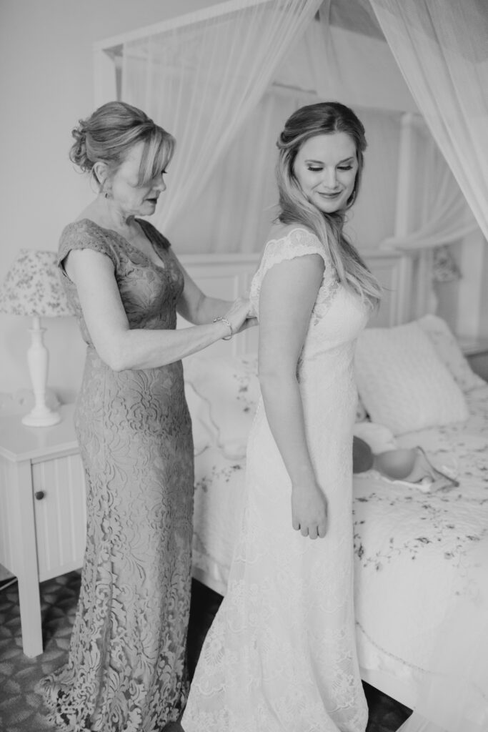 black and white photo of brides mom helping with her dress 