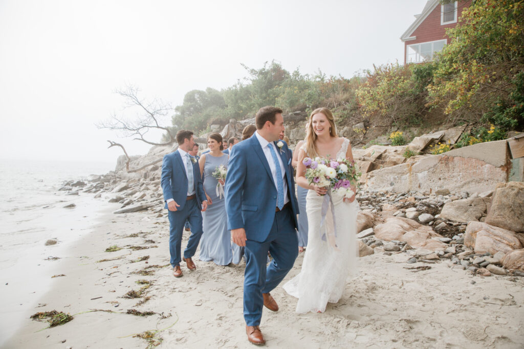 wedding party walking with bride and groom on the beach