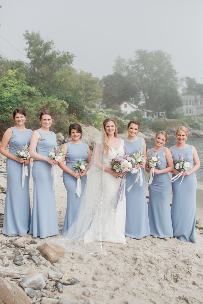 bridesmaids standing with bride wearing long periwinkle dresses