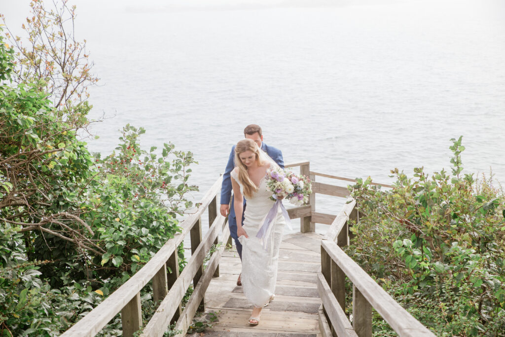 bride and groom walking up walkway from the beach