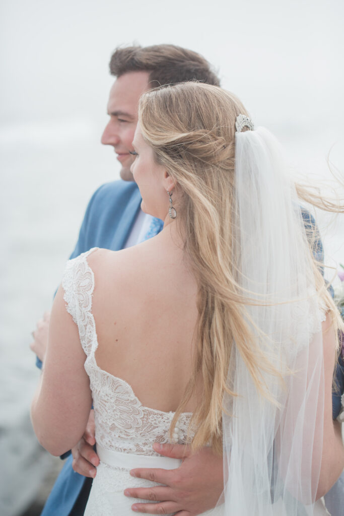 bride and groom on the rocks with the ocean in the background 