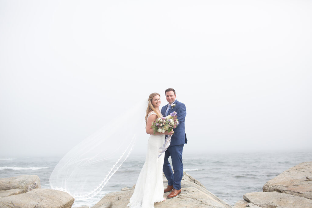 bride and groom on the rocks with the ocean in the background 