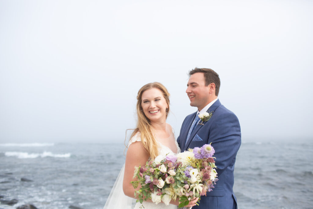 bride and groom on the rocks with the ocean in the background 