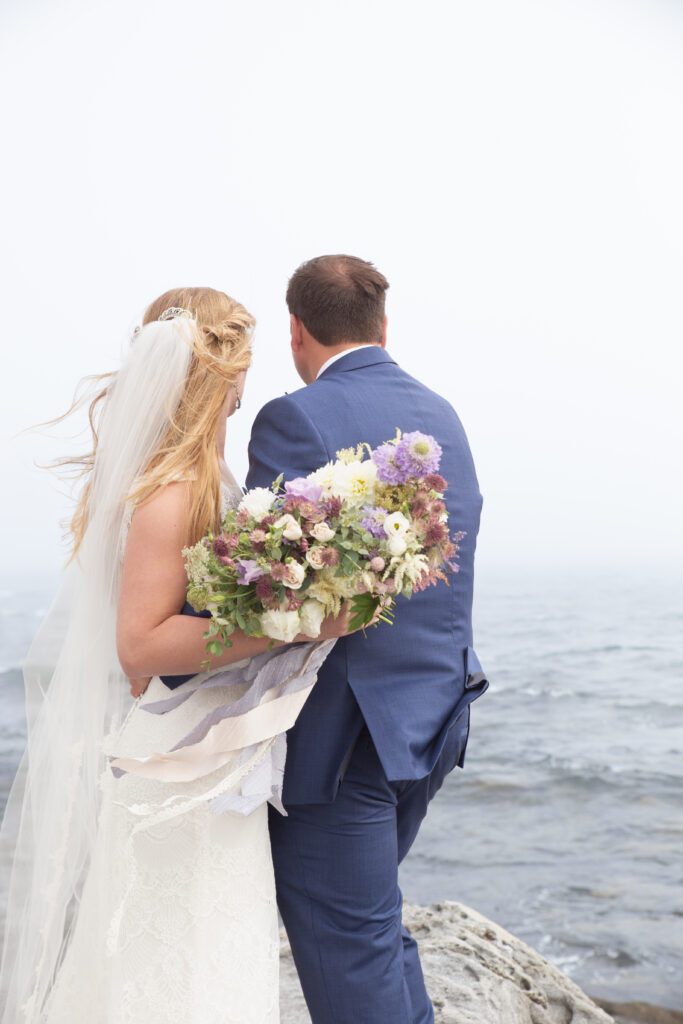 bride and groom looking out at the ocean