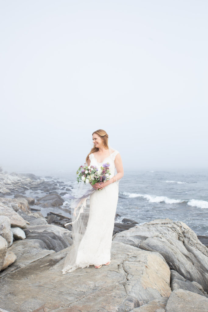 bride on rocks with foggy ocean background 