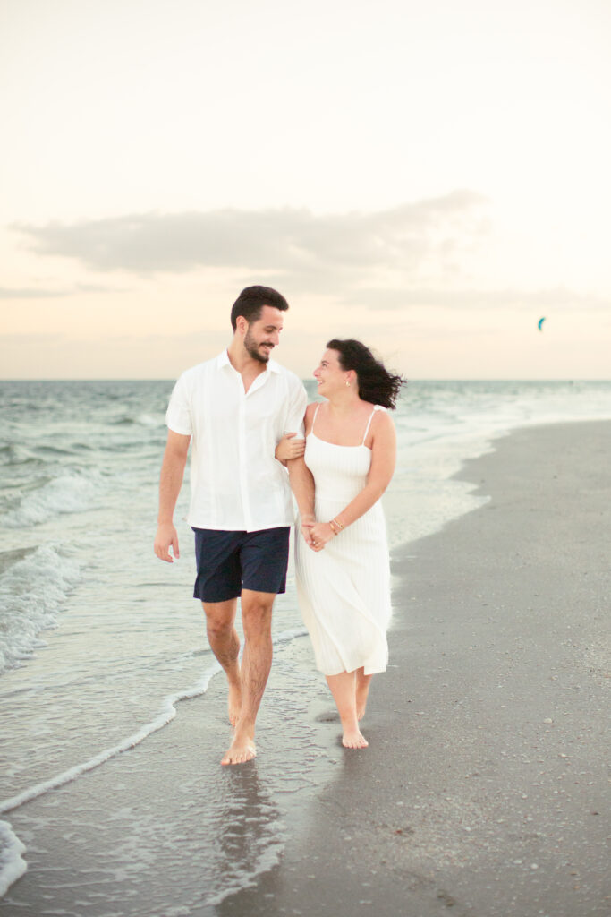 couple walking holding hands with sunset on the beach in the background