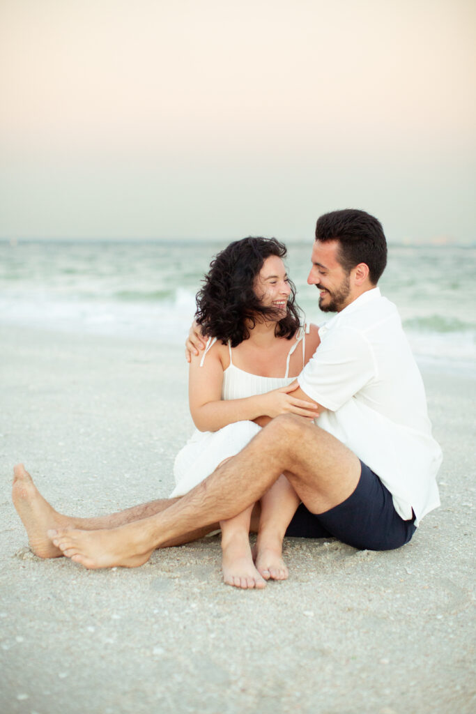 couple sitting on the beach at sunset 