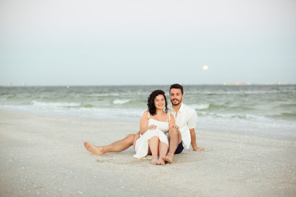 couple sitting on the beach at sunset 