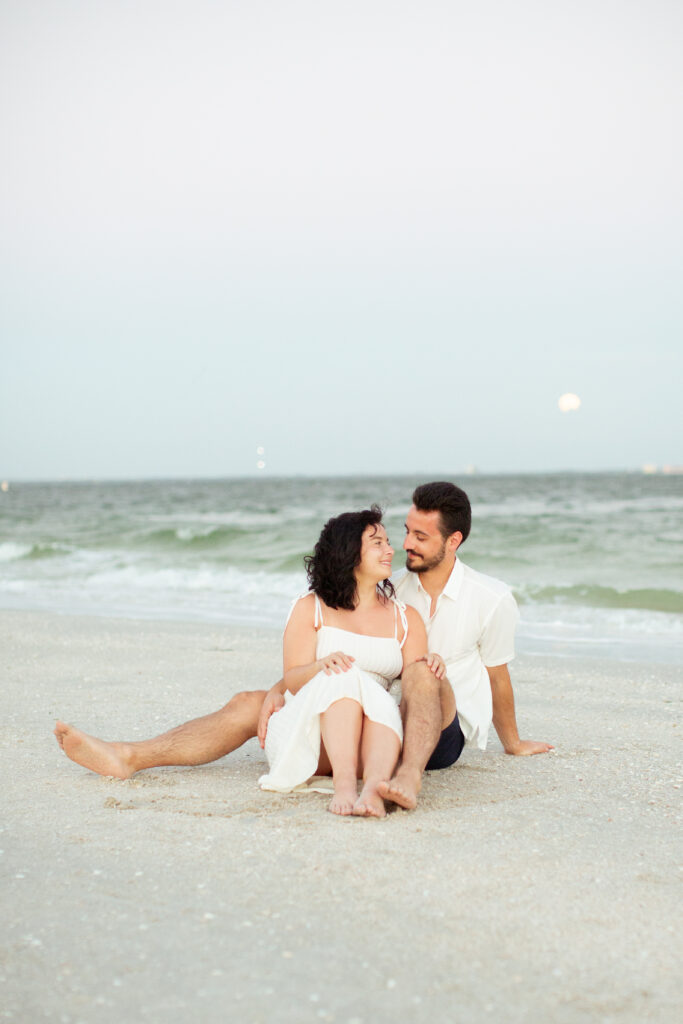 couple sitting on the beach at sunset 