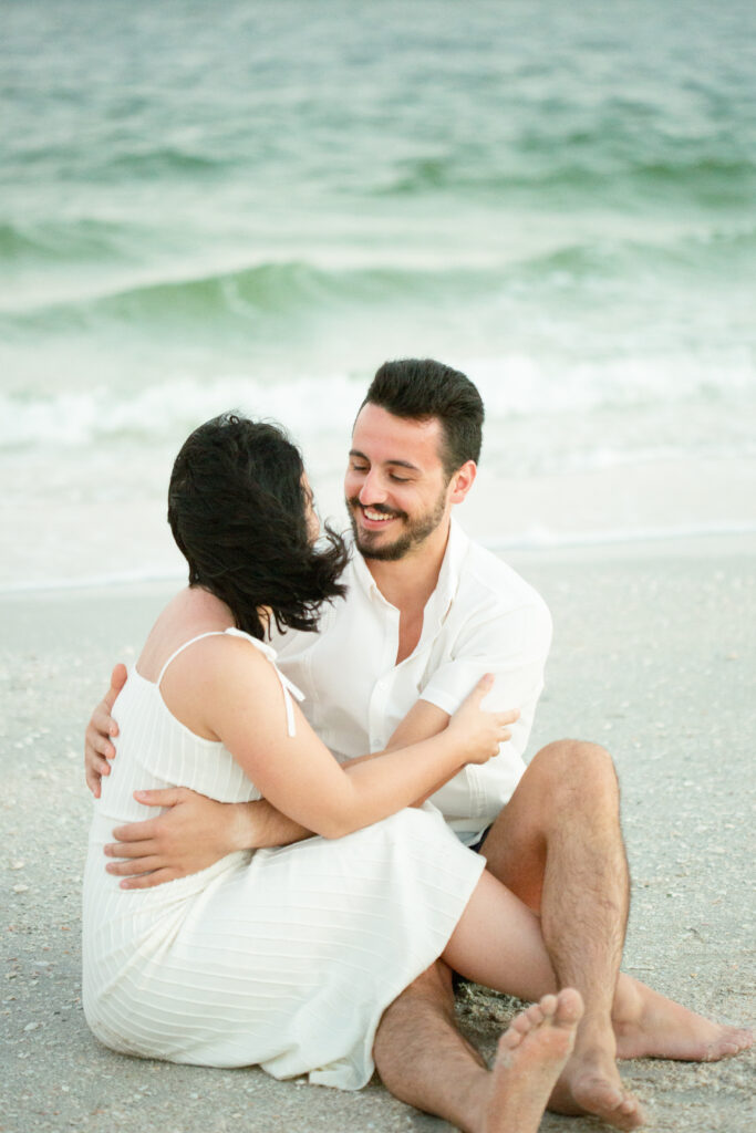 couple sitting on the beach at sunset 