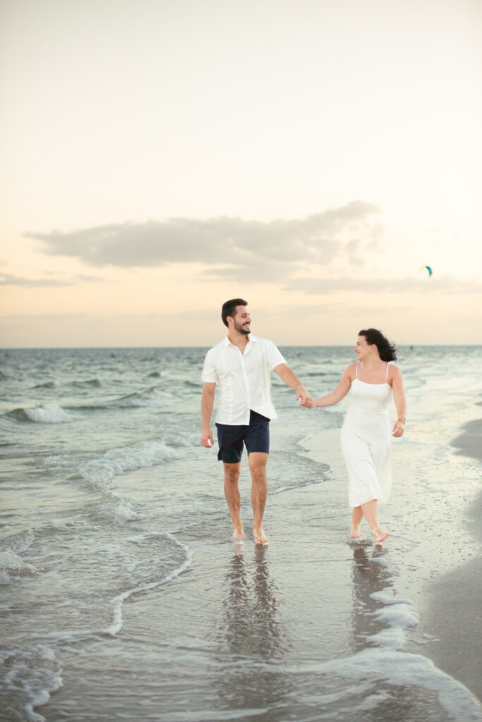 couple walking holding hands with sunset on the beach in the background