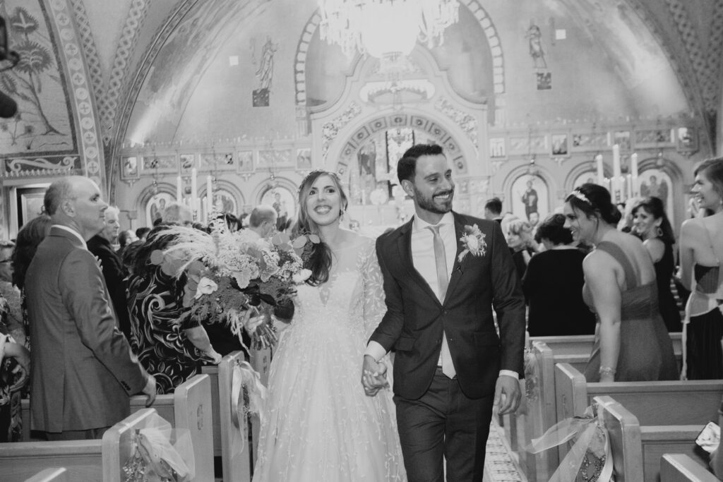 black and white of bride and groom celebrating on their way out of the ceremony 