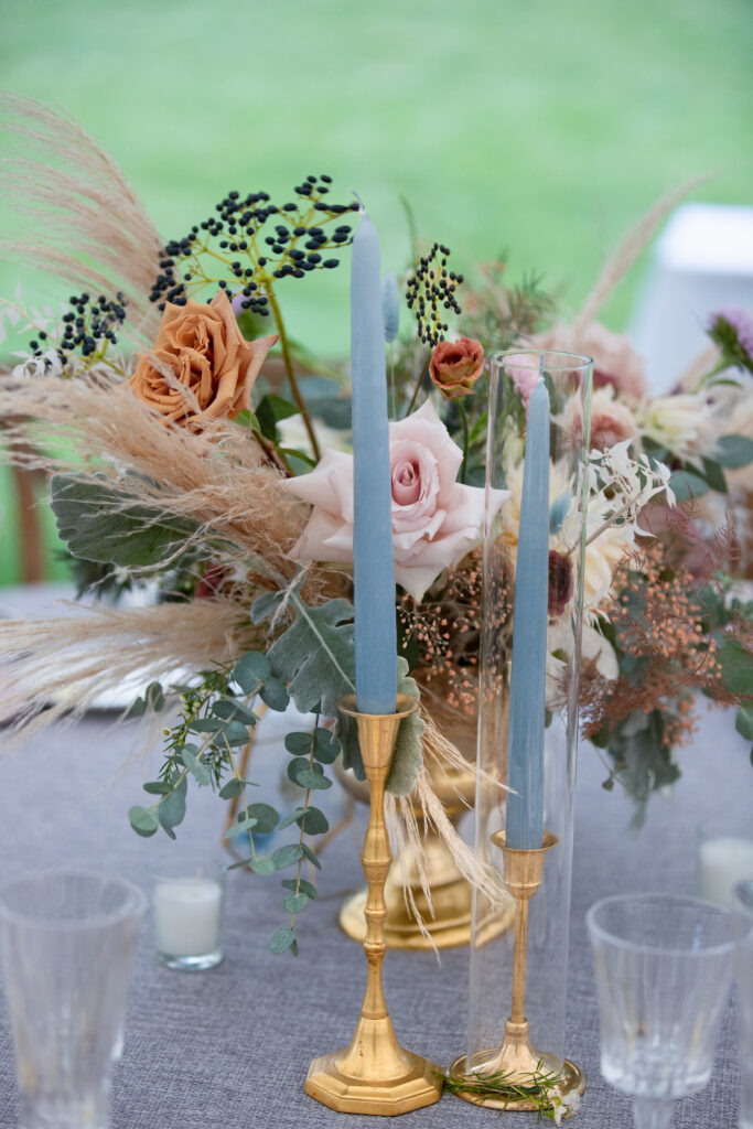 blue tall candles in gold traditional candle holders and florals 