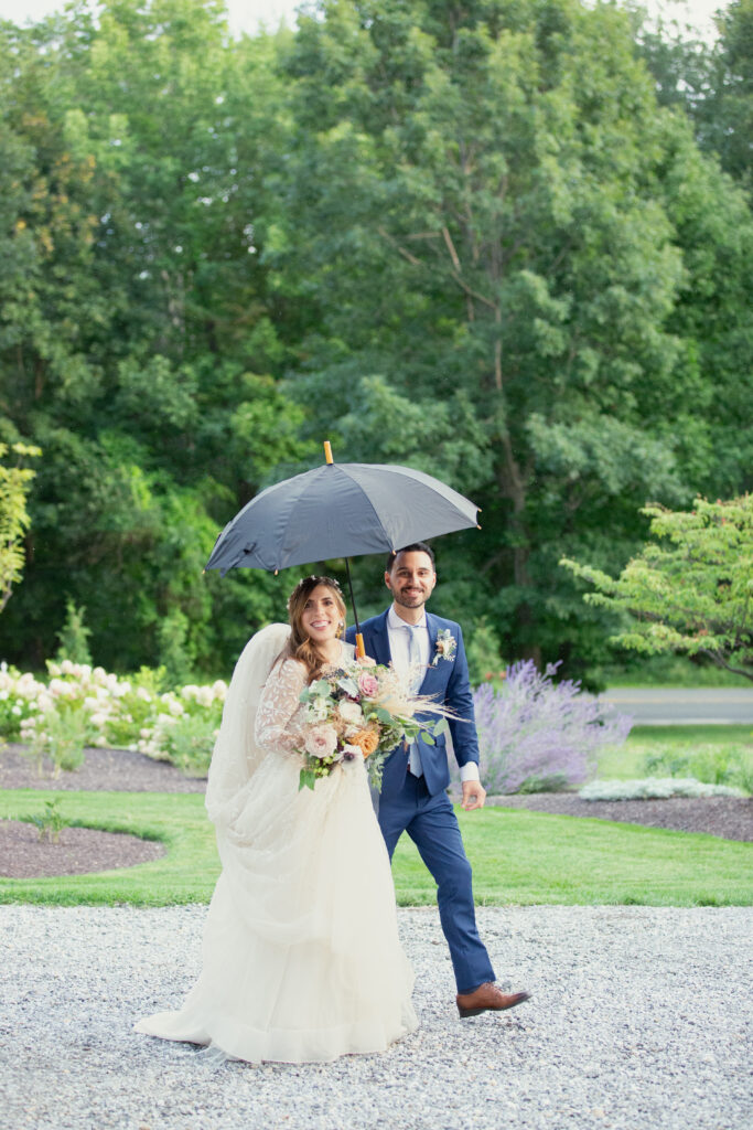 bride and groom walking holding an umbrella 