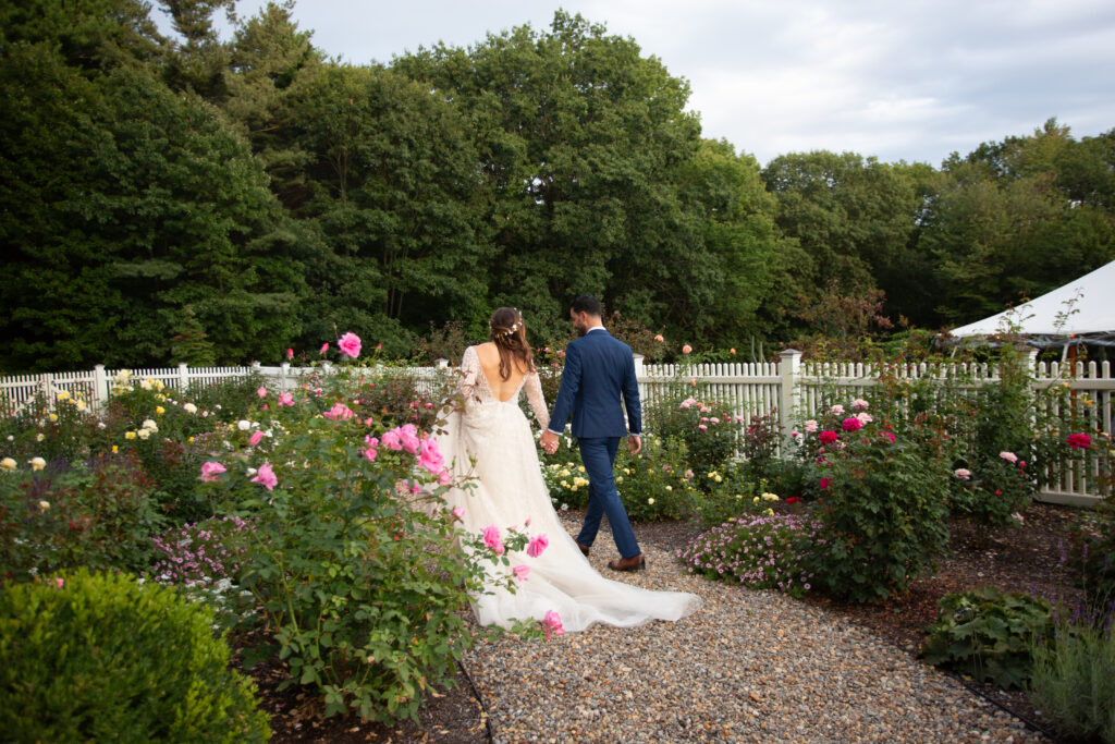 bride and groom walking in the rose garden 