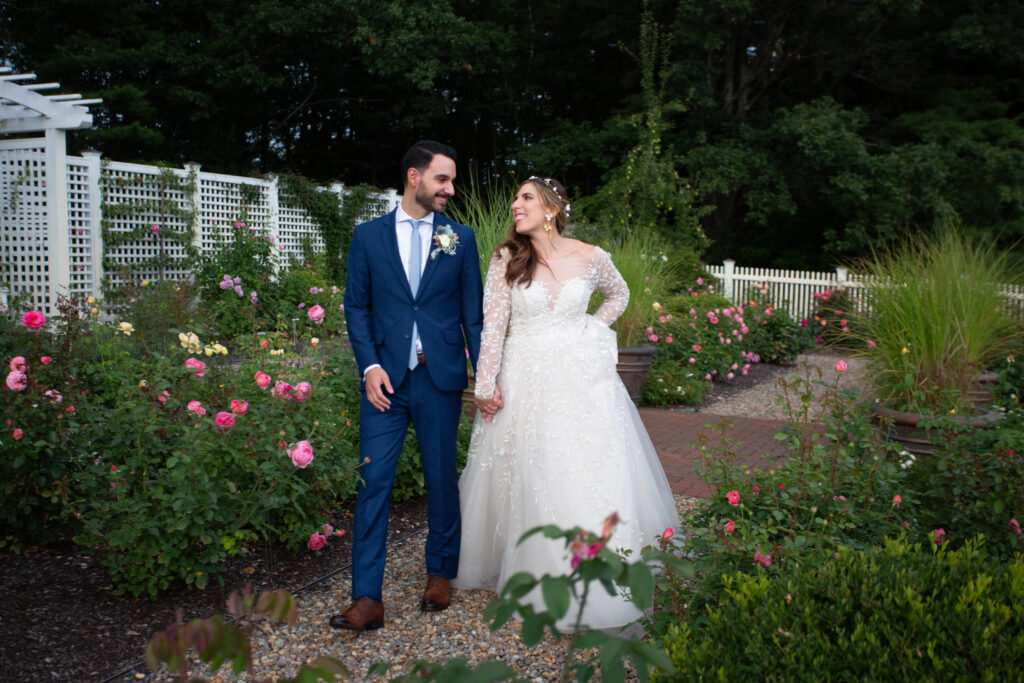 bride and groom walking in the rose garden 