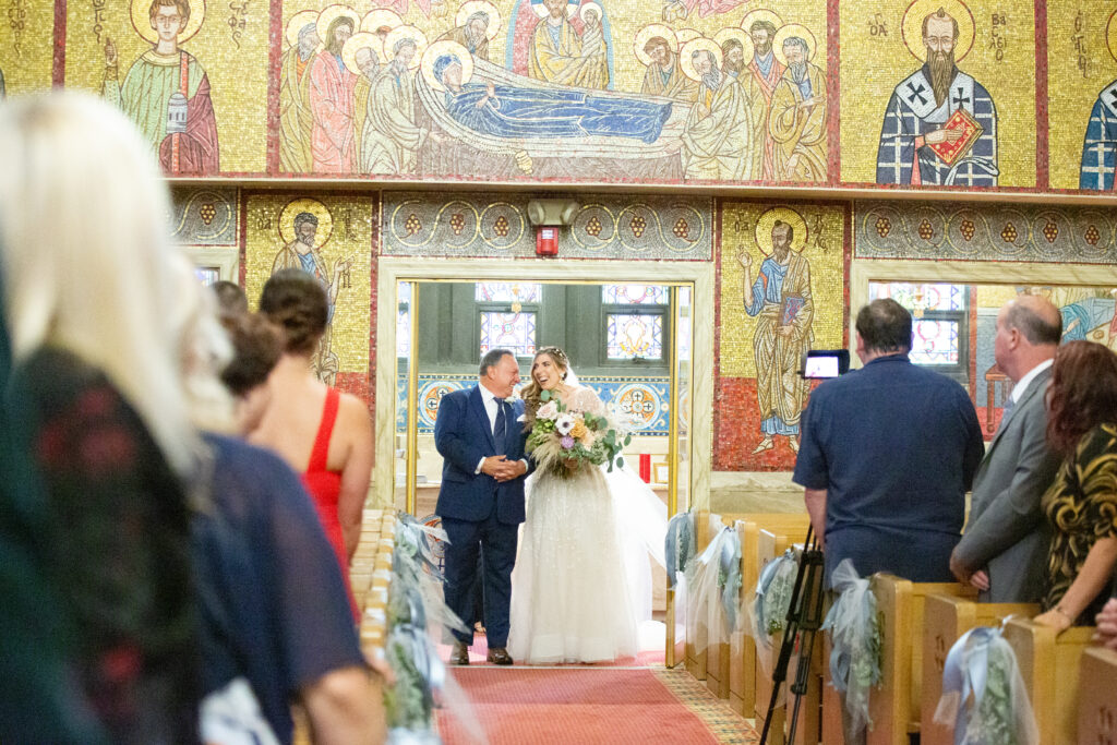 Bride and her dad walking down the aisle of the Greek Orthodox wedding ceremony 