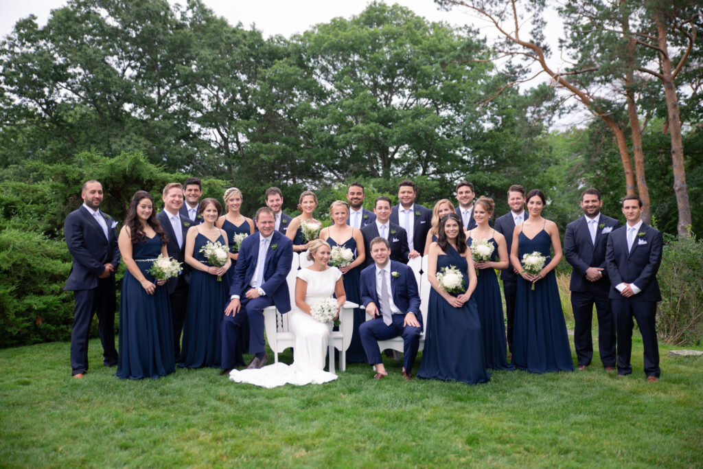 Large wedding party in navy colors standing in the gardens for a picture