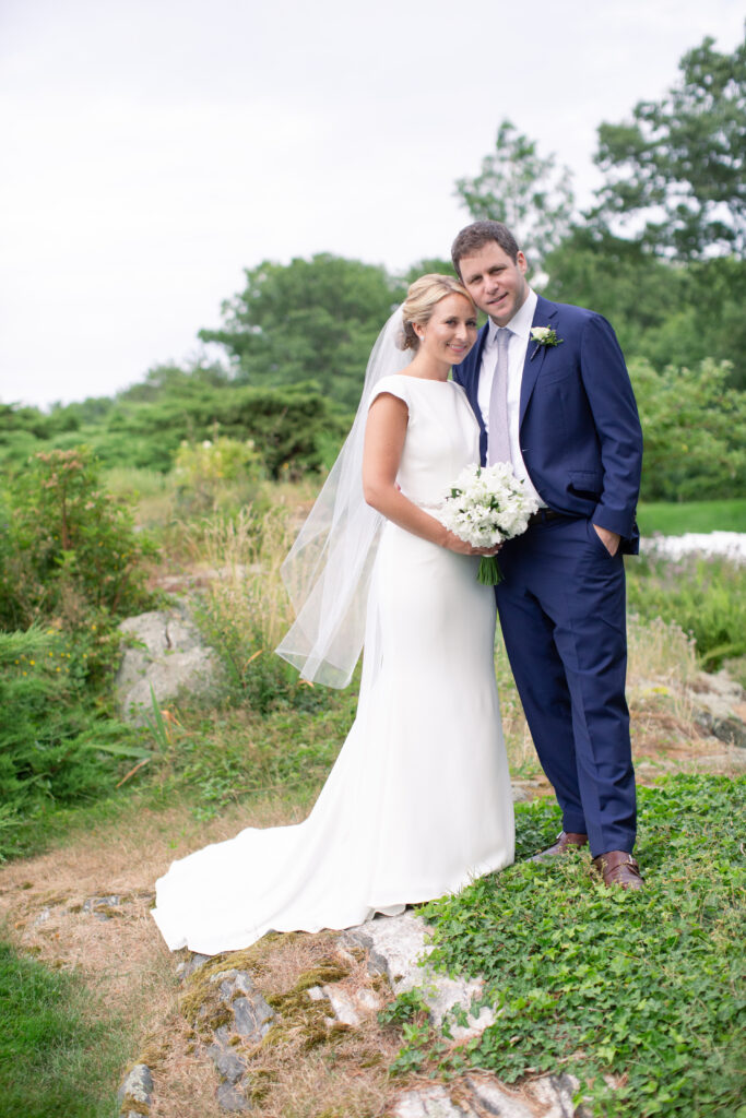 groom in navy and bride standing in the gardens 