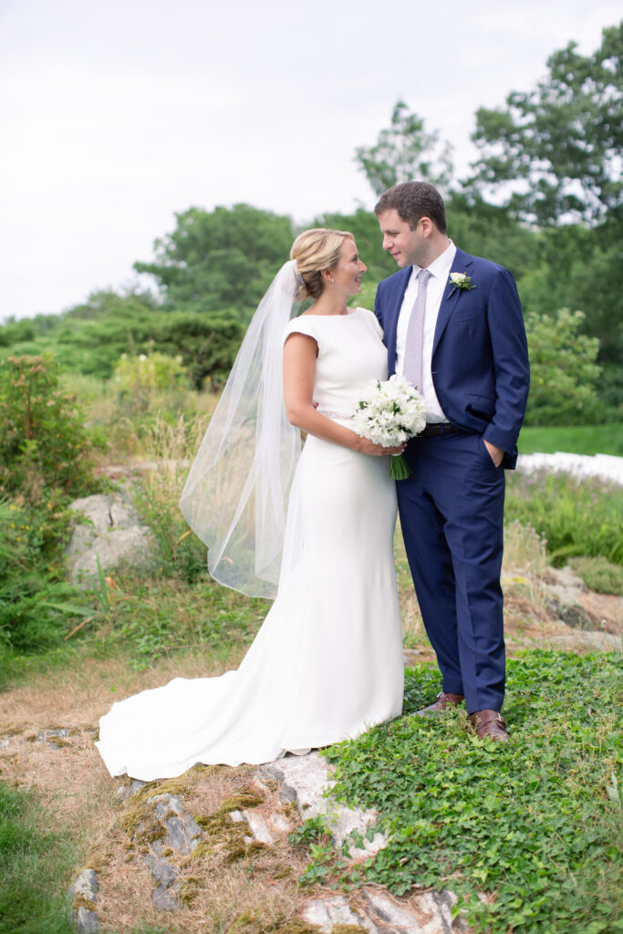 groom in navy and bride standing in the gardens 