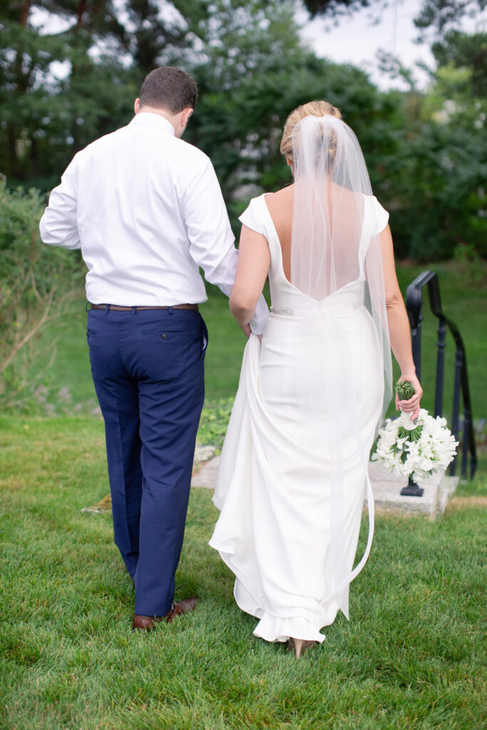 groom in navy and bride standing in the gardens 