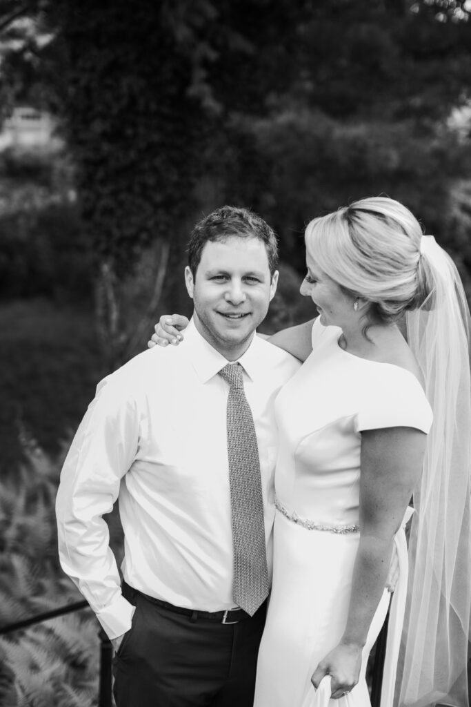 groom in navy suit with bride standing in the gardens 