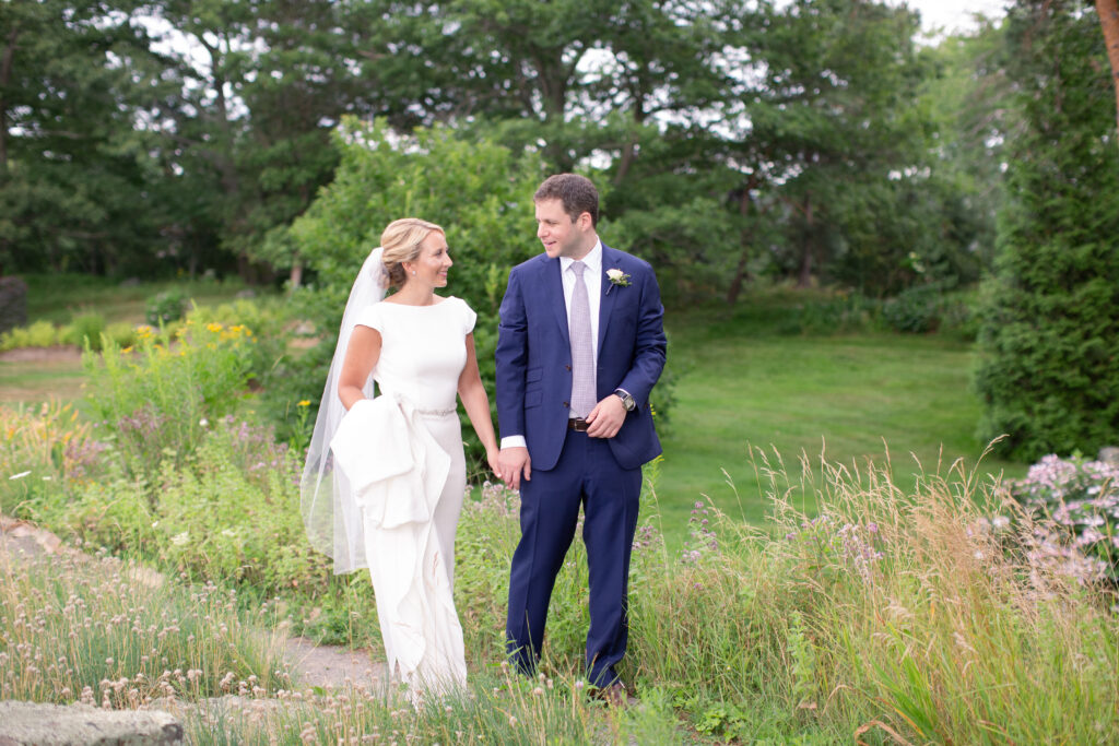 groom in navy and bride standing in the gardens 