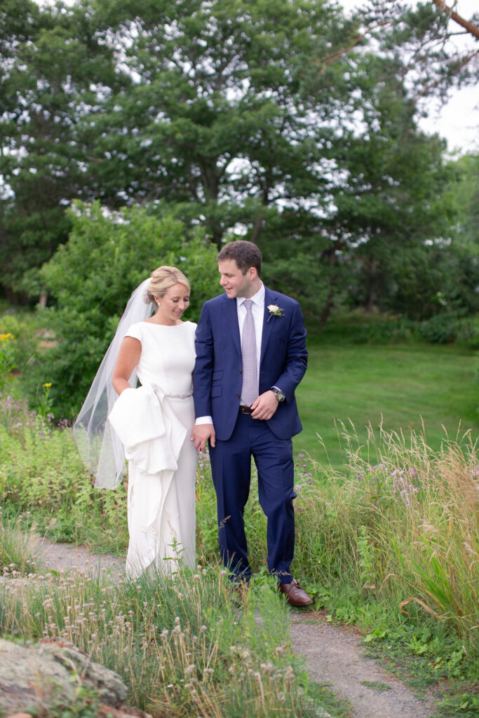 groom in navy suit with bride standing in the gardens 