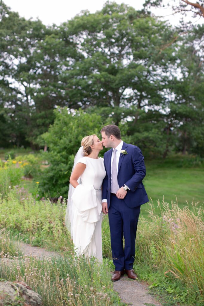 groom in navy suit with bride standing in the gardens 