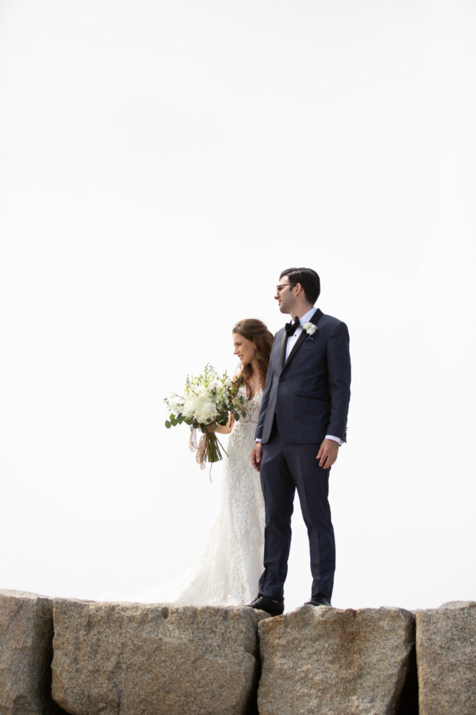 bride and groom walking on rocky jetty