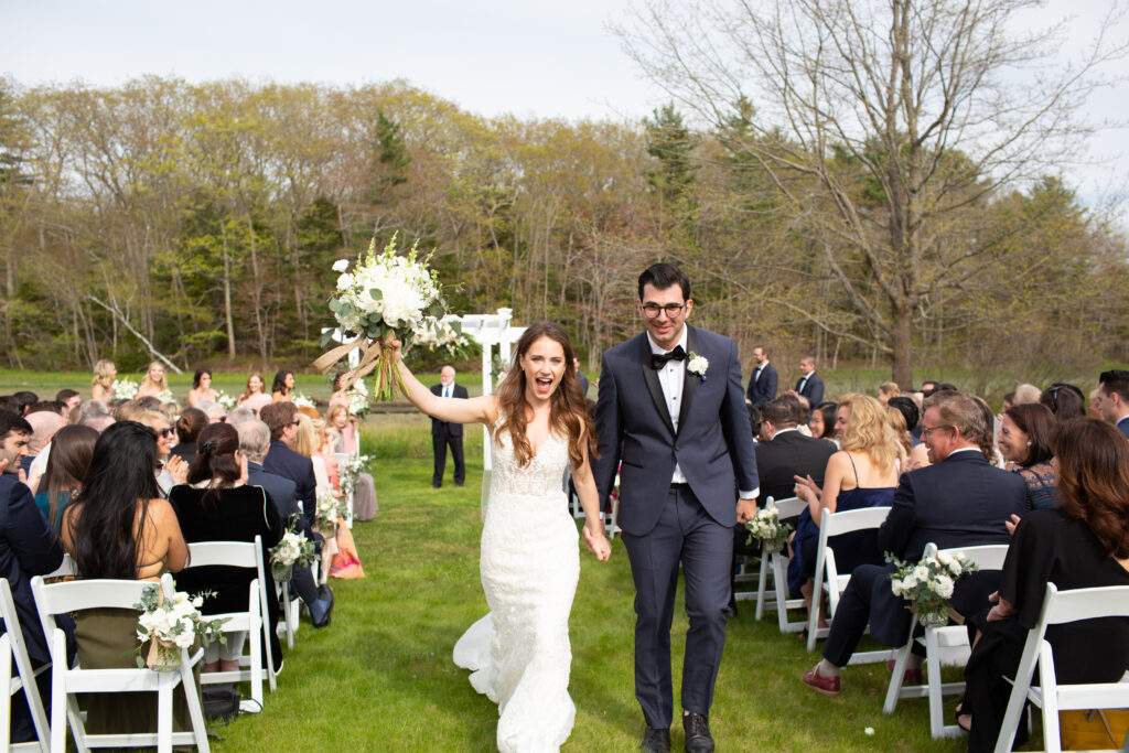 bride and groom celebrating after they are wed walking out of the ceremony back down the aisle 