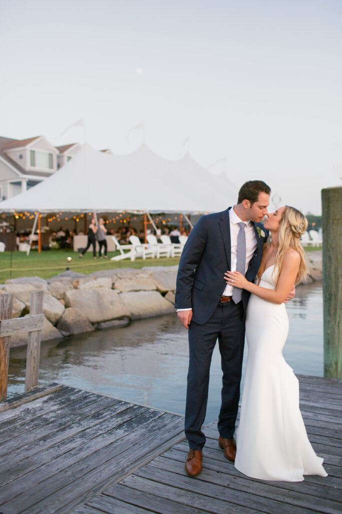 bride and groom on the dock with the tented reception in the background 