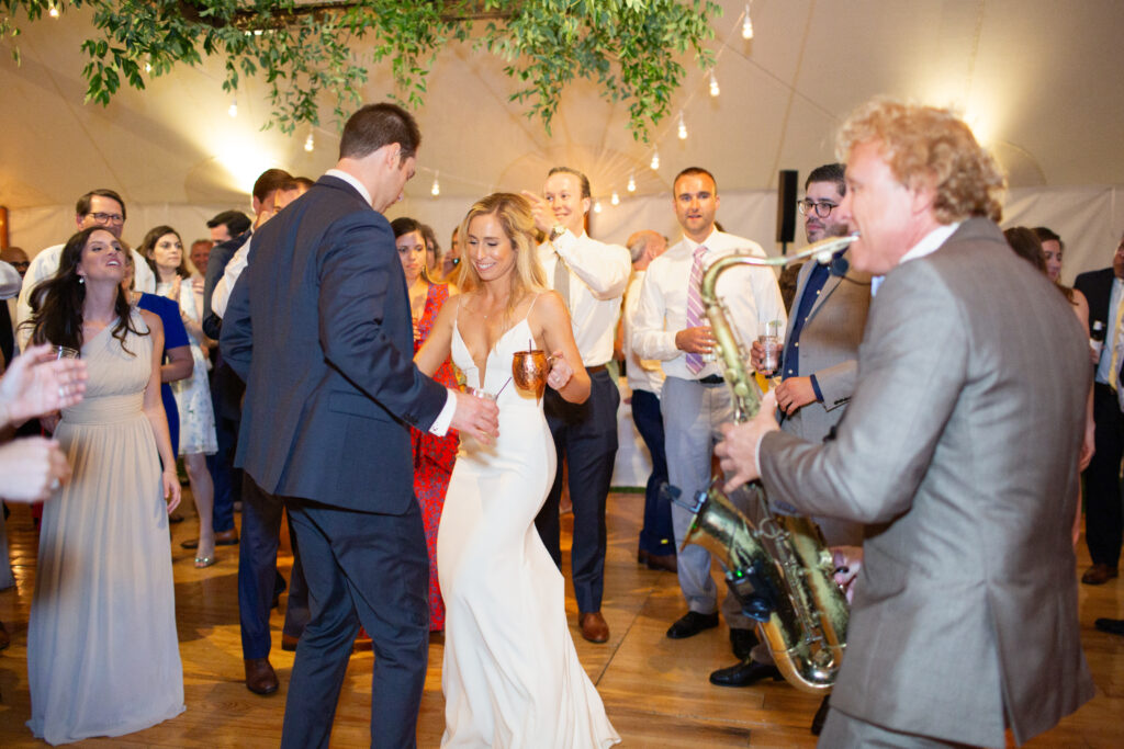 live saxophone player on the dance floor with bride and groom dancing with their guests dancing 