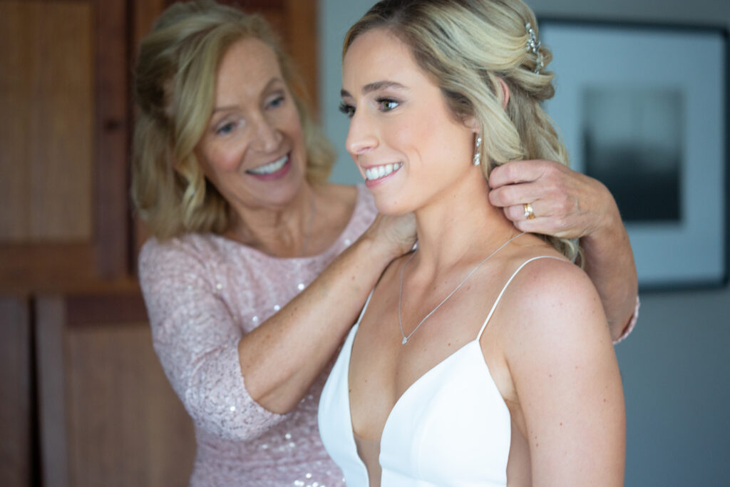 brides mom putting on brides necklace 