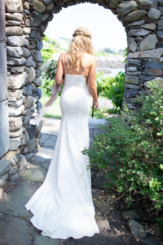 bride walking through stone walkway to see the groom for the first look