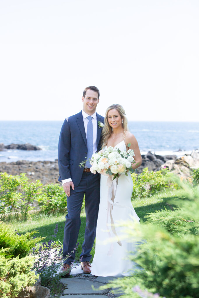 bride and groom looking at the camera with ocean in the background