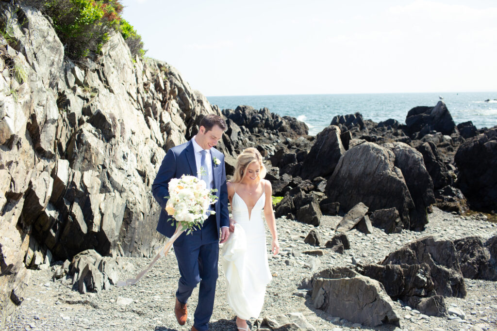 bride and groom walking together on a rocky beach