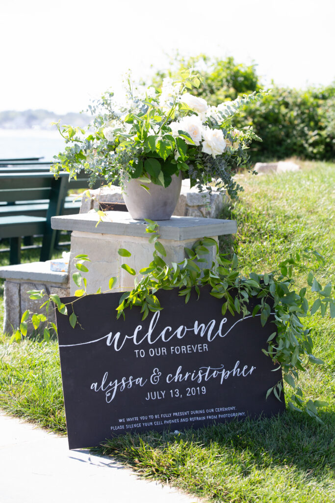 welcome to the ceremony sign with greenery