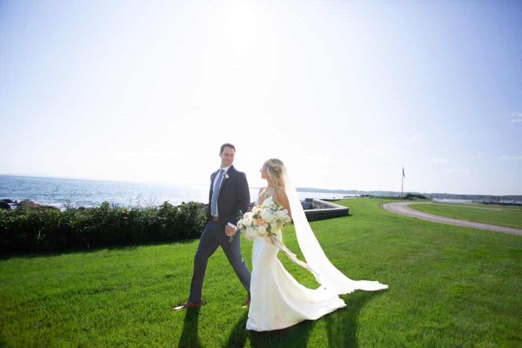 bride and groom walking holding hands by the ocean 